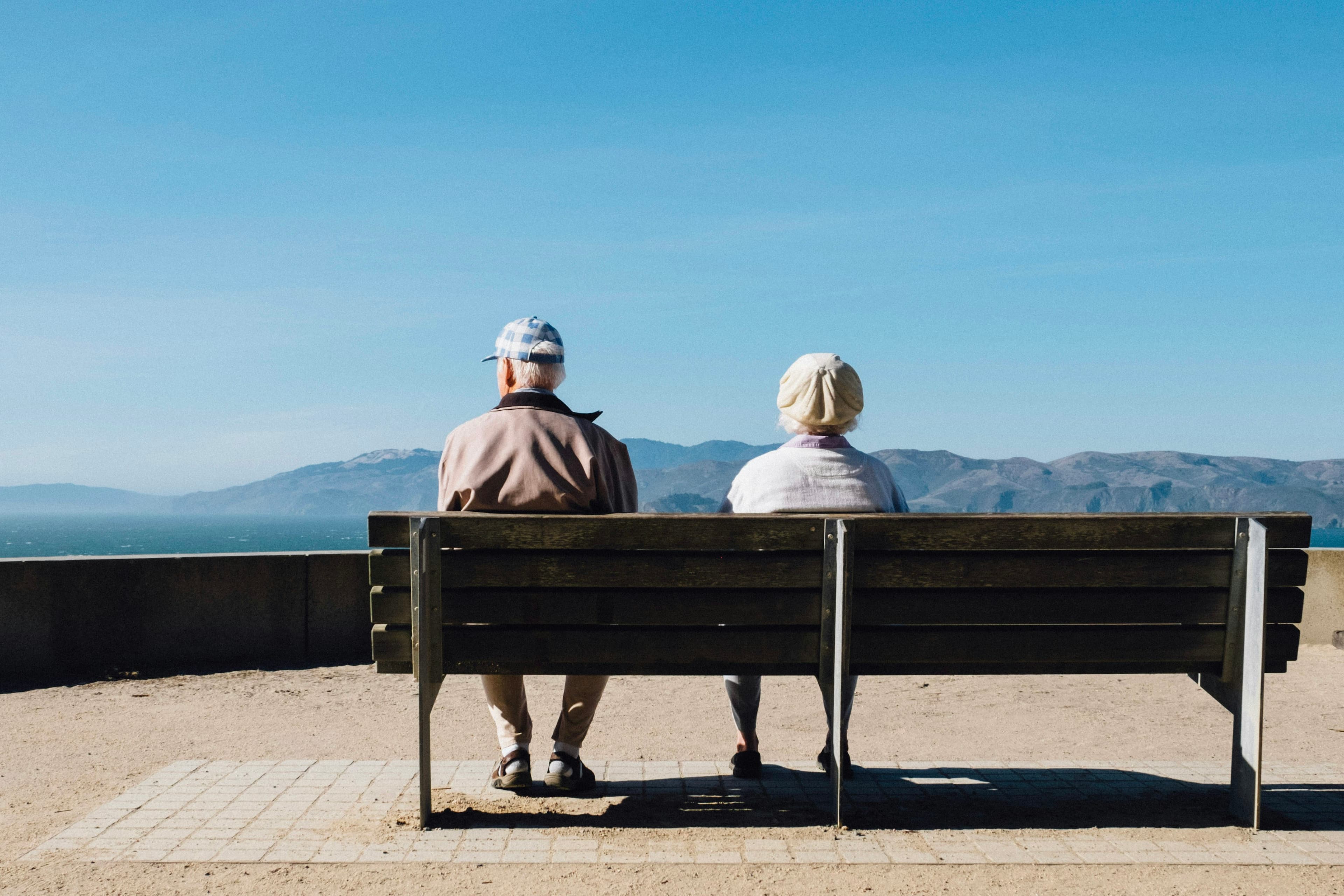 Älteres Paar sitzt auf einer Bank mit Blick aufs Meer
